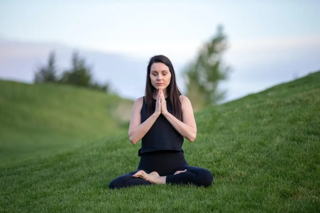 A woman doing yoga on the grass.