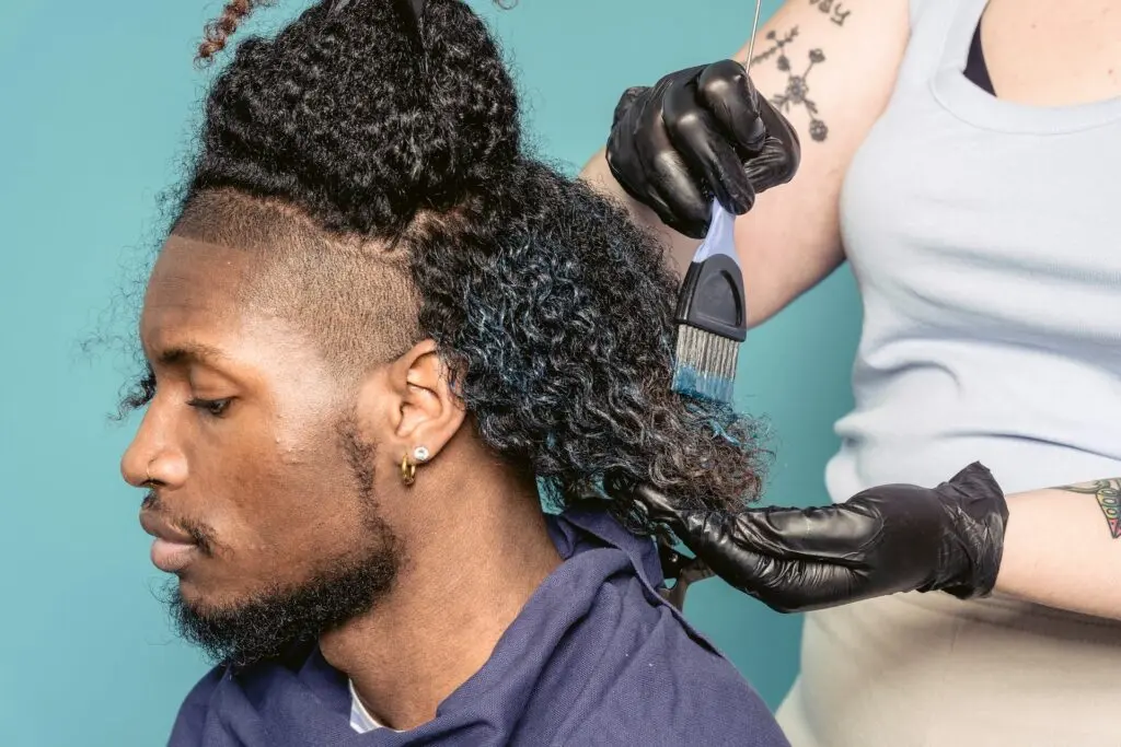 Woman applying blue hair dye to man with curly hair - how to get hair dye off skin