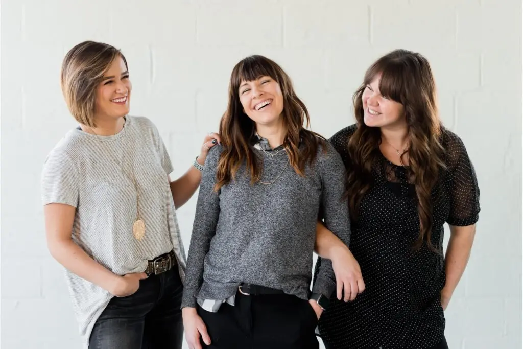 Three women standing and smiling together.