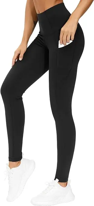 A woman stands on her toes in ankle-length, high-waist black leggings. She holds her phone in one pocket.