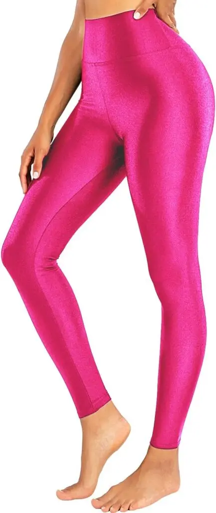A woman stands on her toes in ankle-length, high-waisted pink leggings that have a bright, shiny fabric.