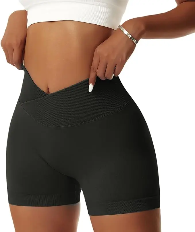 A woman stands in black biking short leggings with a v-shaped waistband. She holds the waistband in both hands like she's pulling her shorts up.