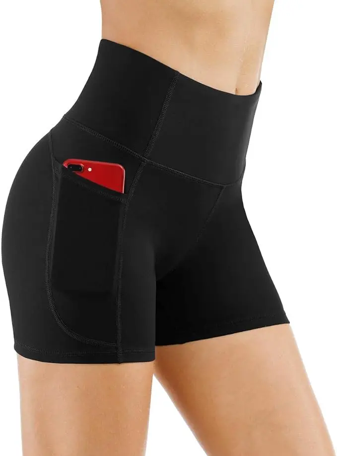 A woman stands in black legging shorts with a red smartphone in one pocket.