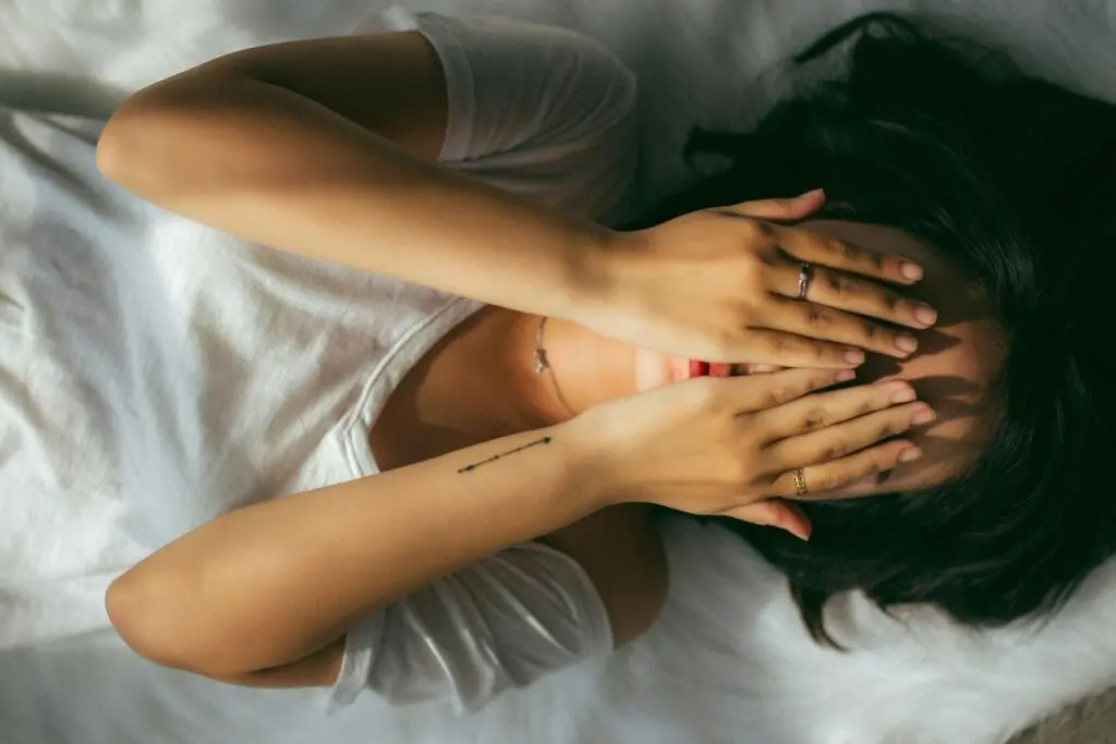 Lady hiding face with hands, showing discomfort.