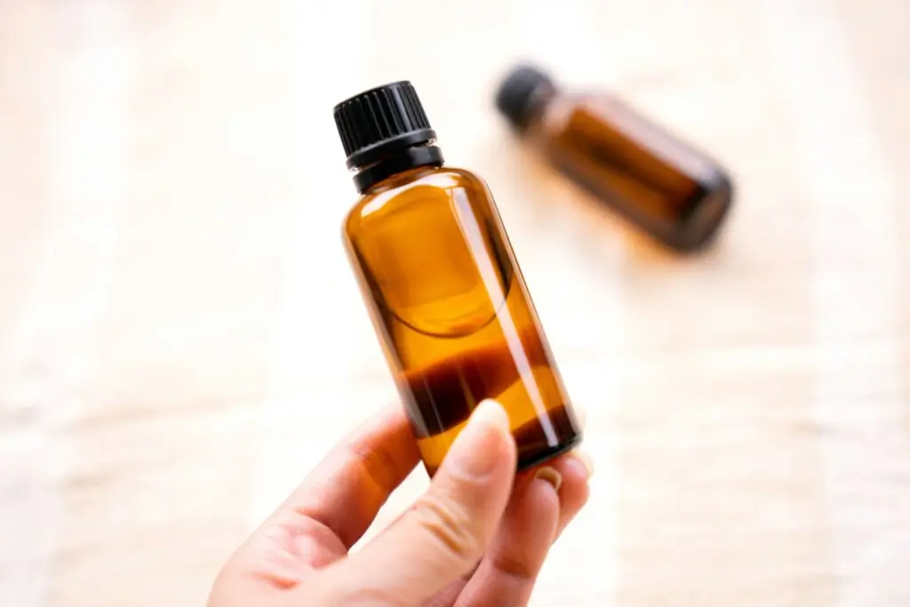 A person holding a small bottle of oil.