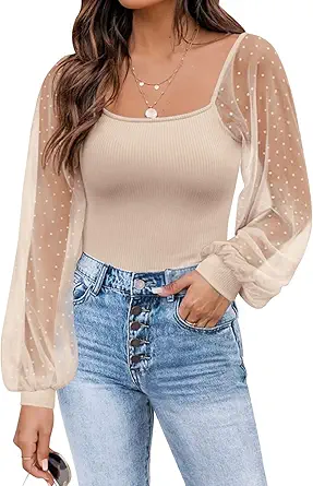 A woman in high-waisted jeans and a silver necklace wears a knit blouse with polka-dot mesh sleeves.