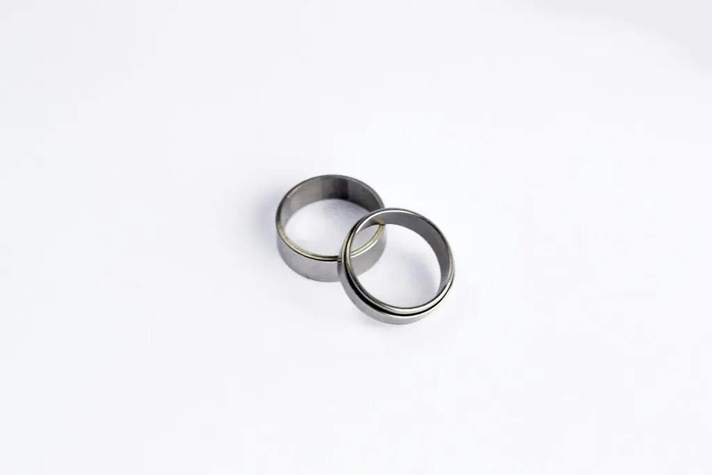 Two silver rings sit on top of each other below the camera on a white surface.