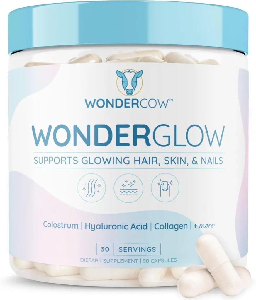 A clear bottle of WonderCow WonderGlow supplements with a light blue lid sits against a white background. Two white capsules sit in front of it on the right side.