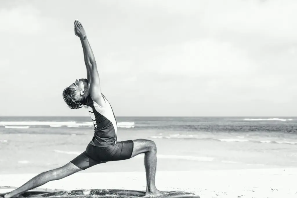 A man doing yoga on the beach.