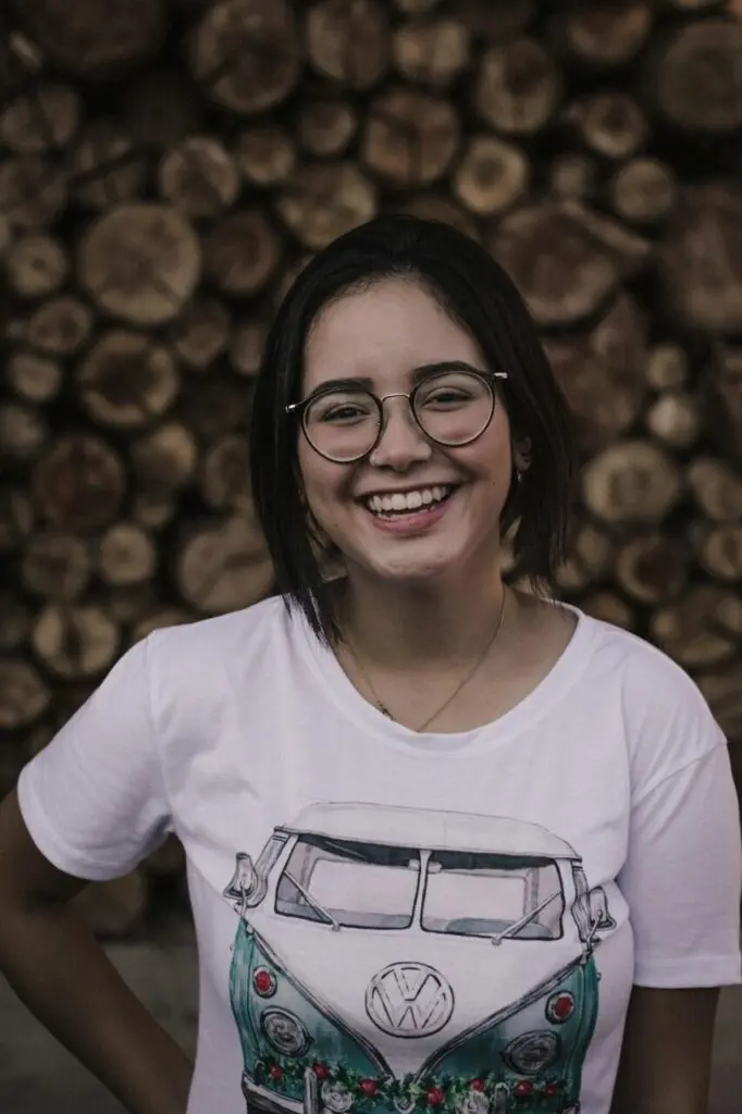 A girl in spectacles wearing a white t-shirt and smiling