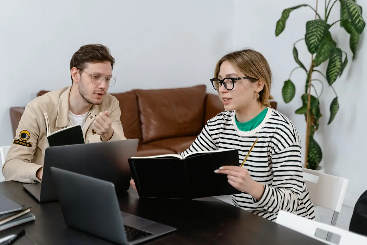 A man and woman in spectacles reading a book excerpt