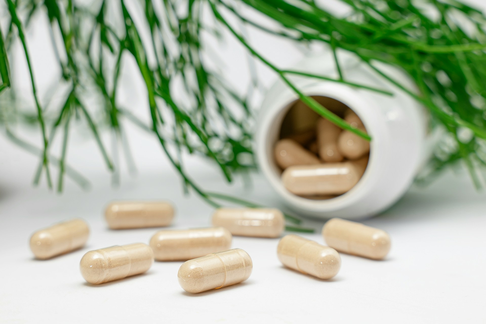 A supplement bottle with tablets spilled on the table in front of it