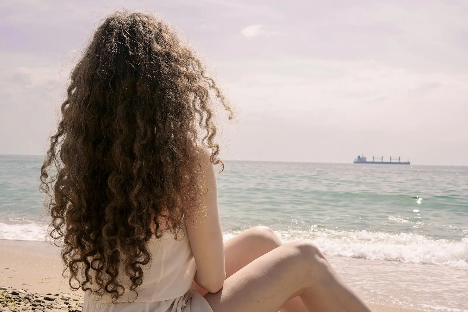 curly haired woman on a beach
