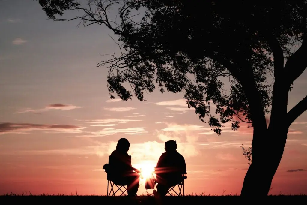 A couple sitting on chairs by the sunset.