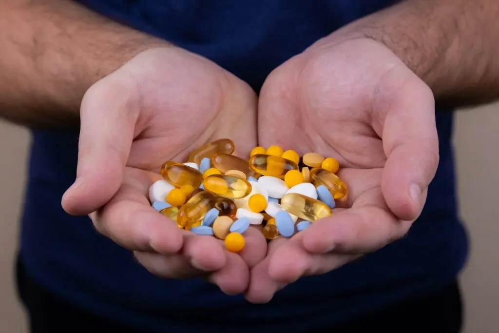 person holding several types and colors of medicine pills