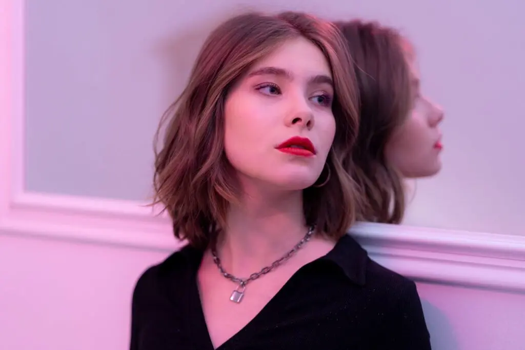 A woman leaning against a wall with a well-defined jaw