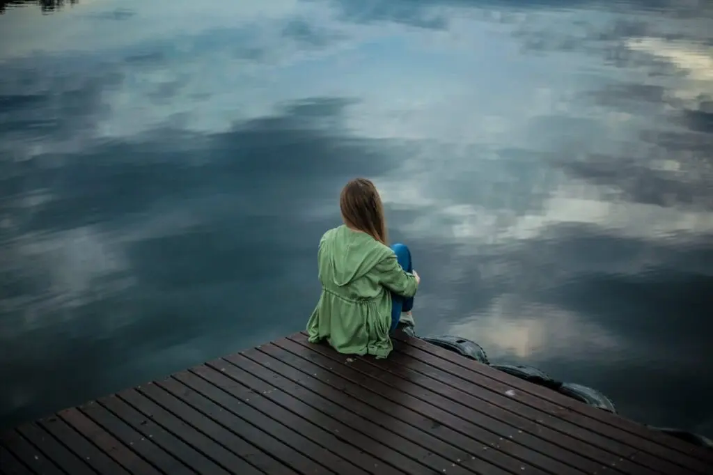 A woman in deep thought sitting on a dock