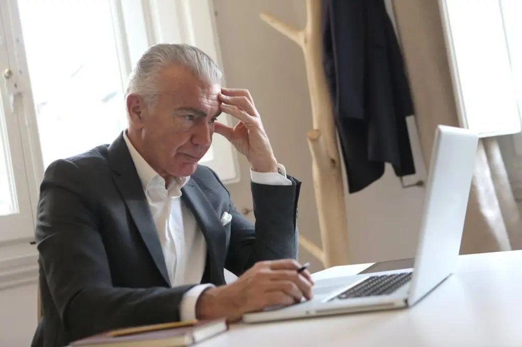 An older man sitting in front of a work laptop