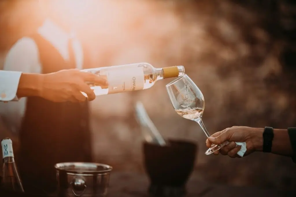 A person pouring wine into another person's glass