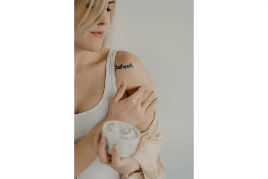 A woman applying an exfoliating scrub to her arm