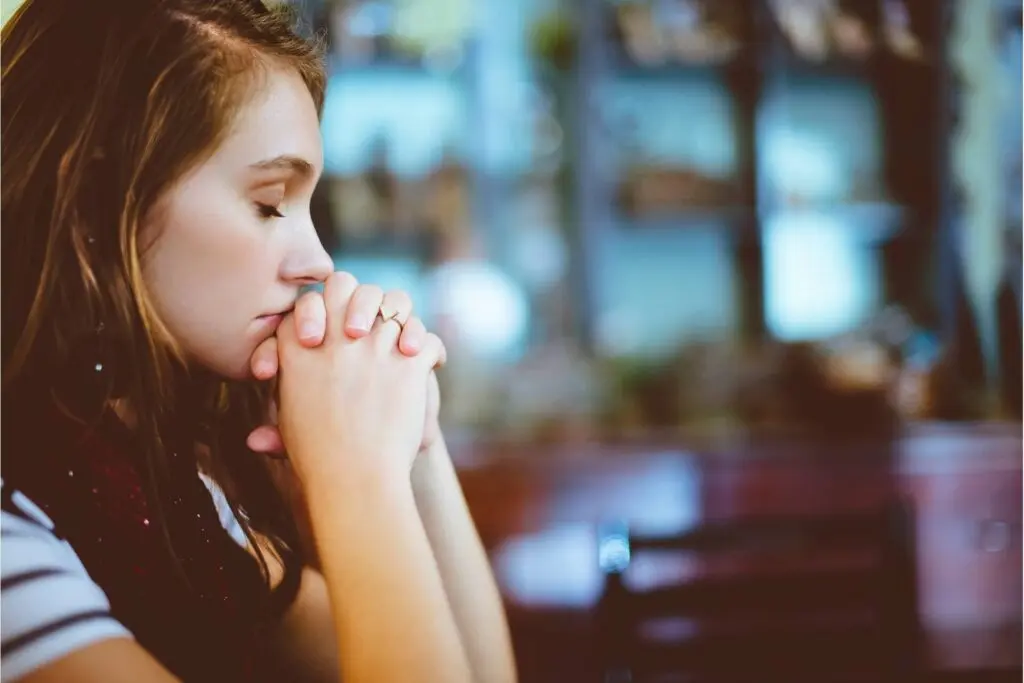 An upset young woman with her eyes closed resting her head on her hands.