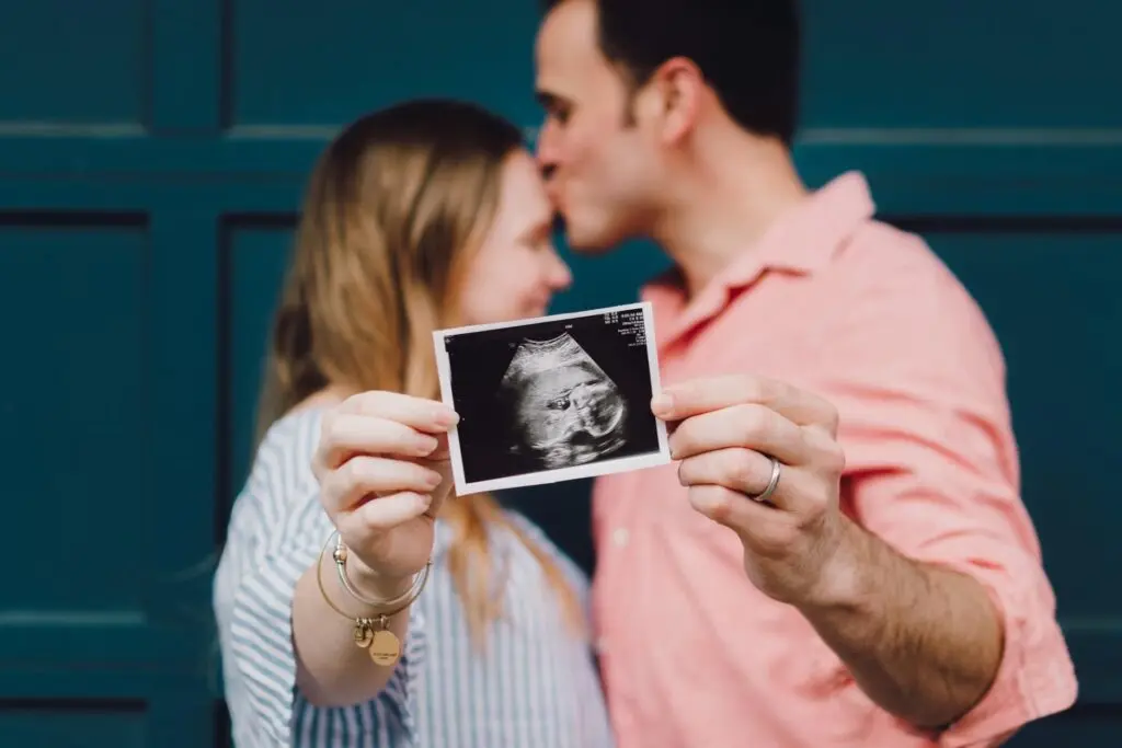 man and woman holding ultrasound photo for the camera