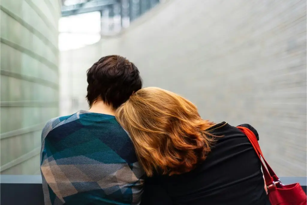 Two friends leaning on one another for support