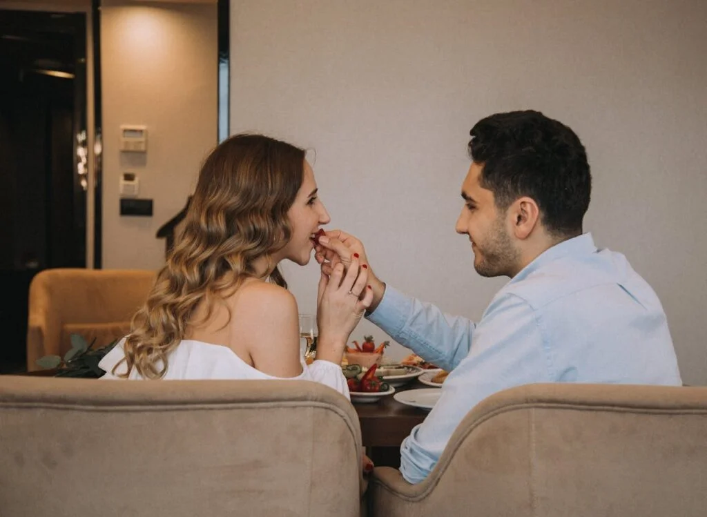 A Couple Sitting at the Table and Eating Together