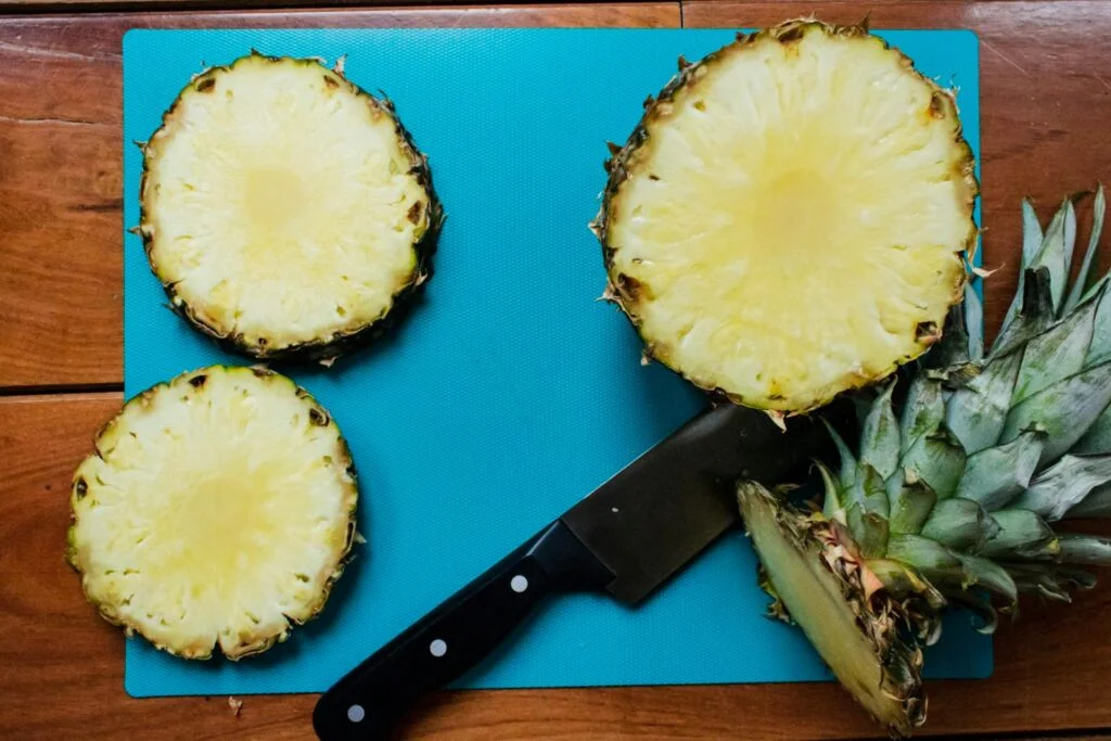 Cut pineapple on blue board with knife