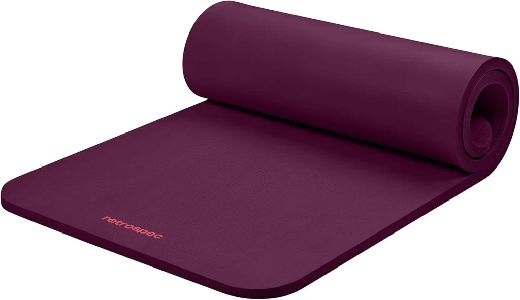 A burgundy yoga mat sits slightly unrolled against a white background. It's perfect for anyone learning how to start Pilates as a beginner at home.