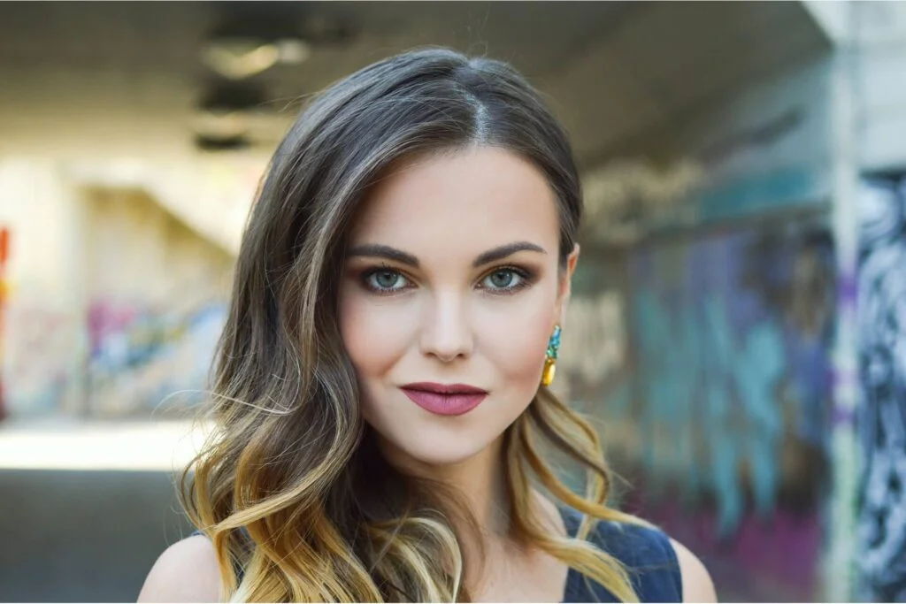 A young woman with dark hair and blonde highlights smirking at the camera