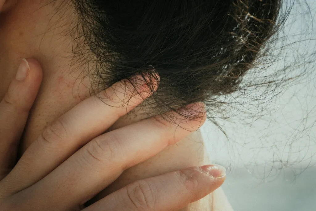 A hand gently touches the person's neck and hair