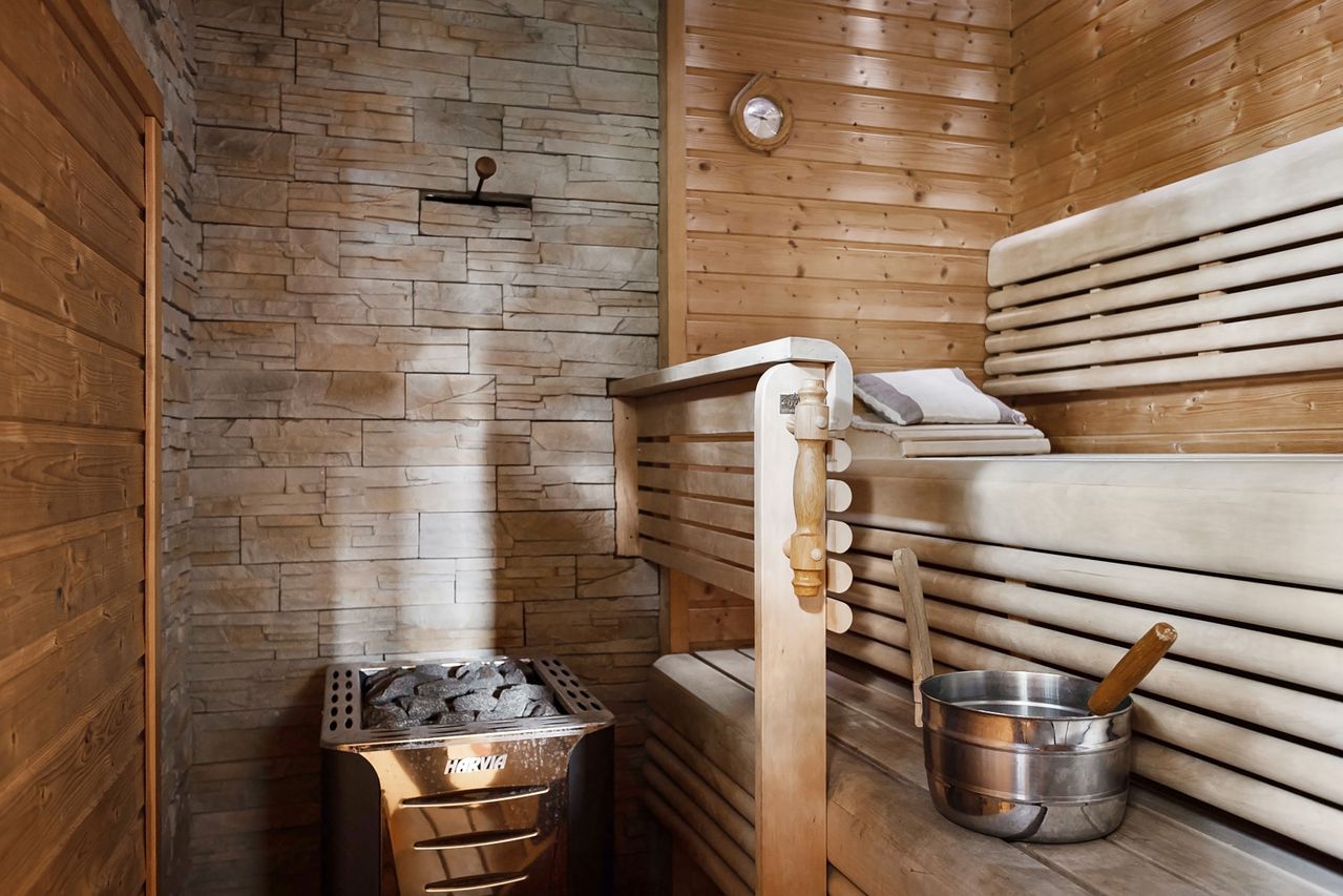 Featuring a relaxing sauna interior with wooden benches and a stone wall heater for a serene escape