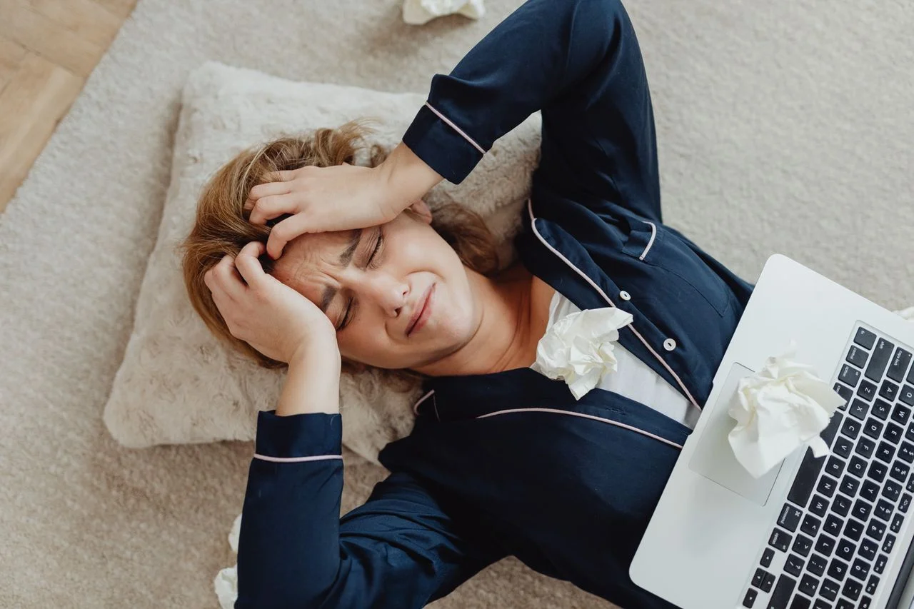 Overhead view of a frustrated woman in loungewear with a laptop and crumpled papers, facing remote work stress