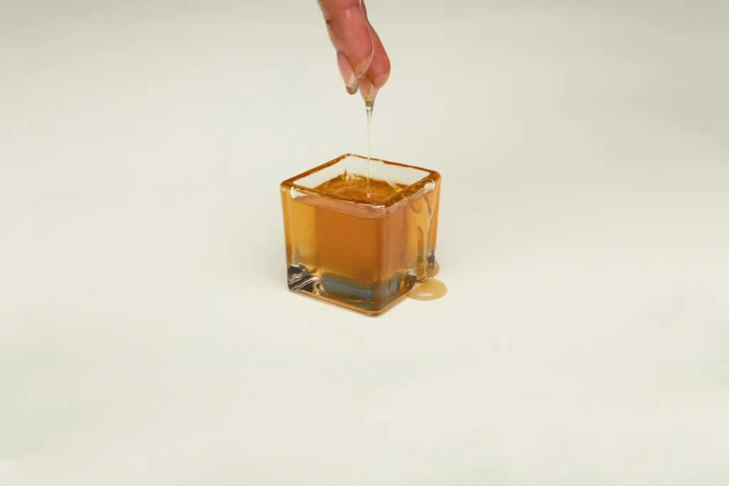 A person sticking their fingers in a jar of syrup