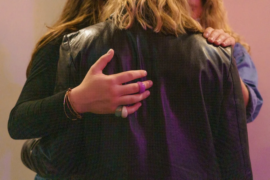 Two people offering comfort by placing their hands on another person's arms
