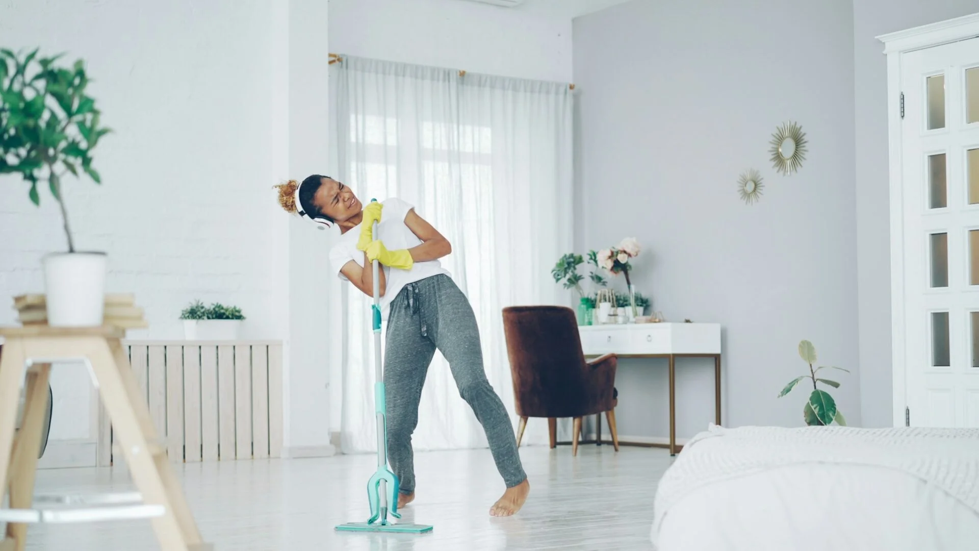 woman mopping the floor while singing and dancing
