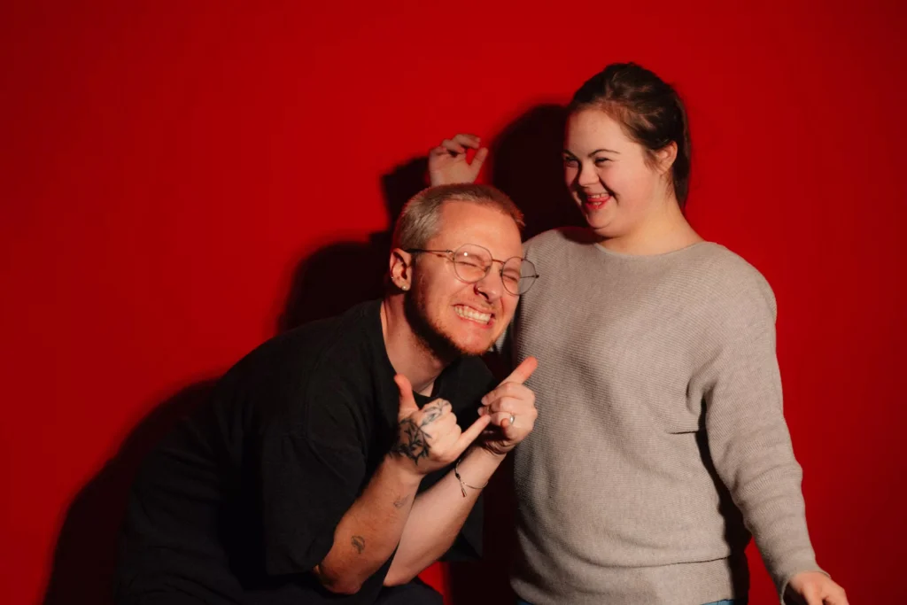 two people grinning on a red background