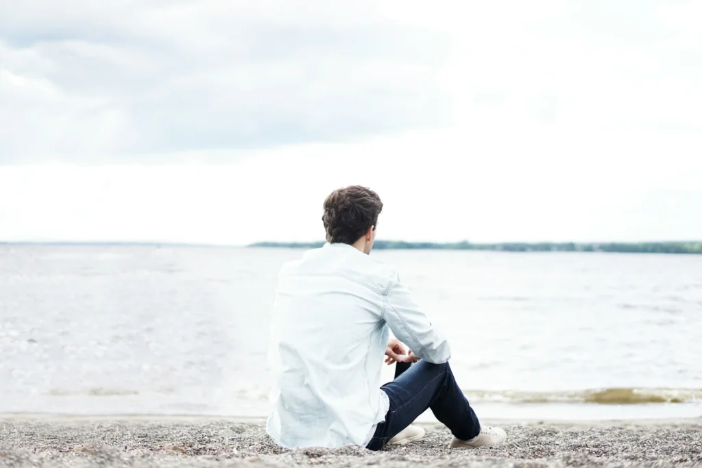 A man staring off into a large body of water, reflecting while cooling-off from his relationship