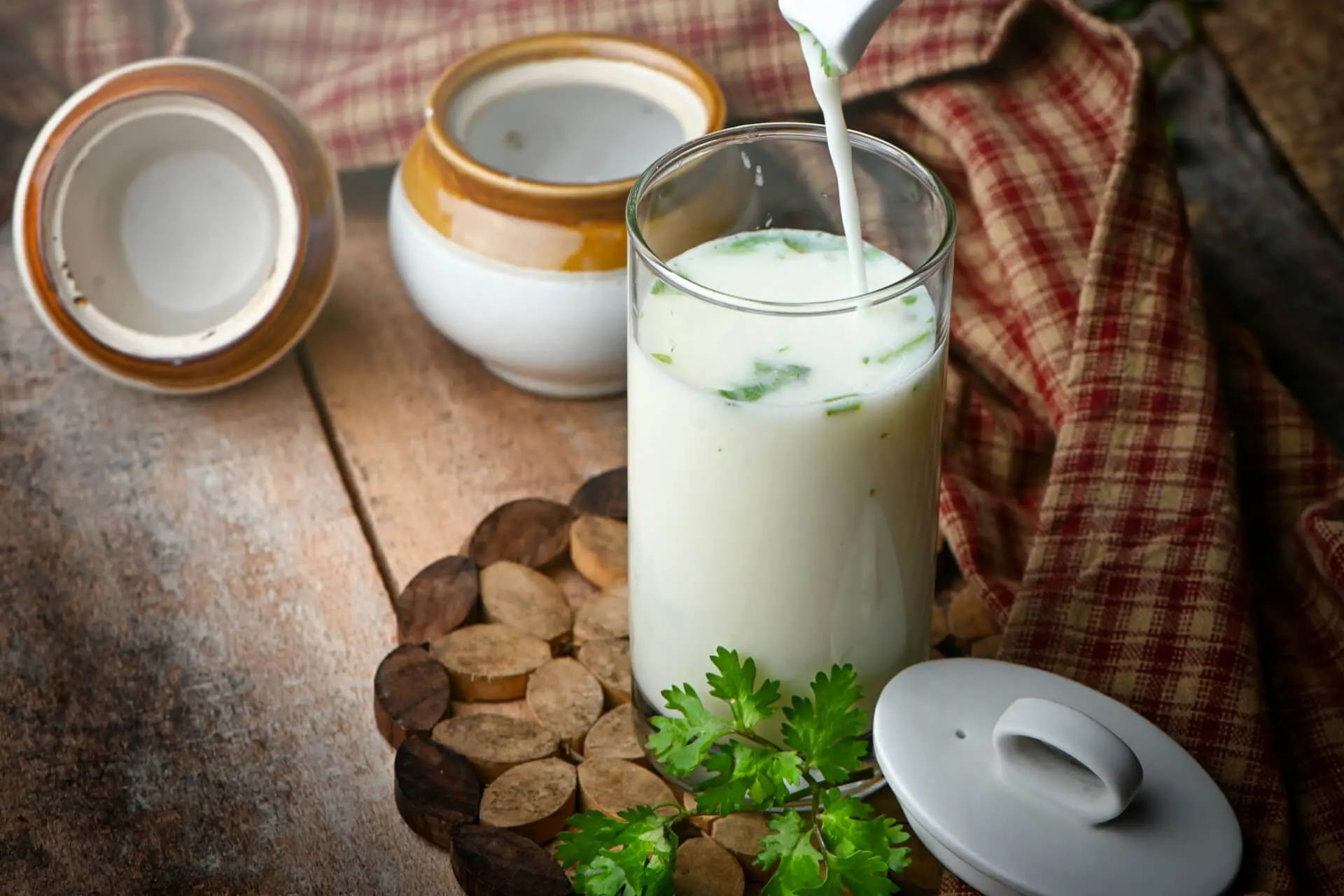 A glass of milk-based fermented drink garnished with fresh herbs and cream