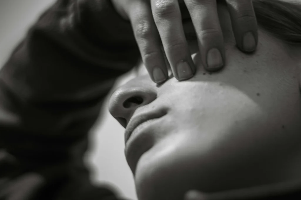 Black and white photo of woman with fingers on her face