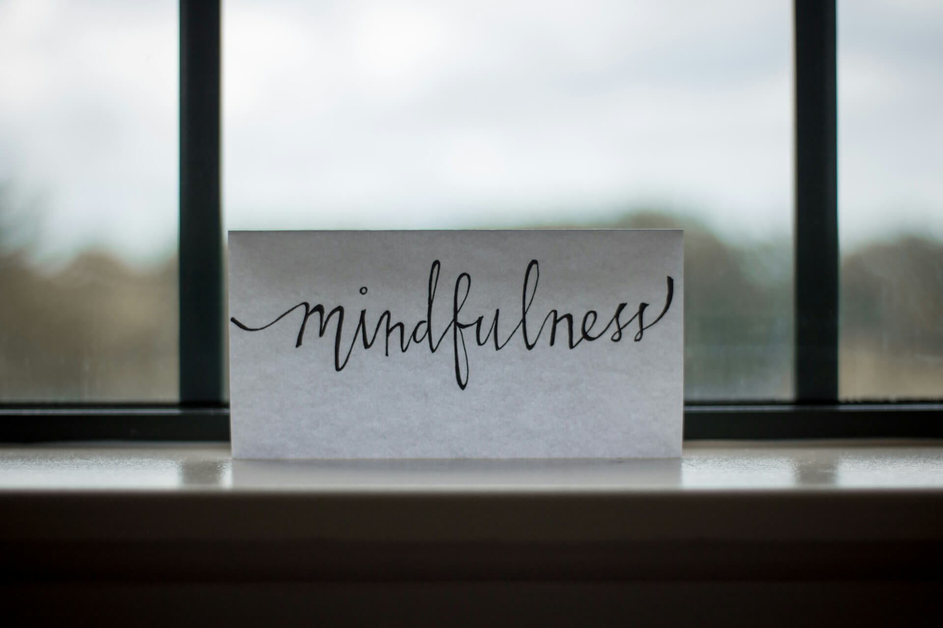 Close-up of a paper with the word 'mindfulness' typed on it, sitting near a sunlit window