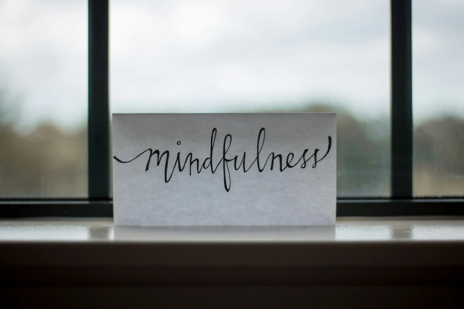 Close-up of a paper with the word 'mindfulness' typed on it, sitting near a sunlit window