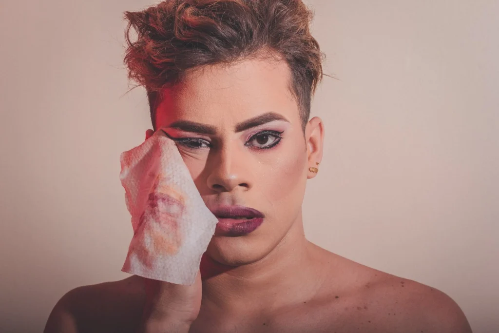 Model with a tissue pressed to his face after applying makeup
