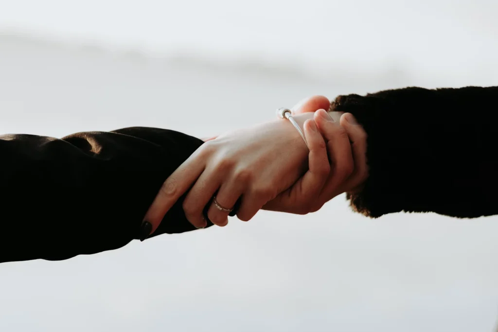 people with black sleeves holding hands