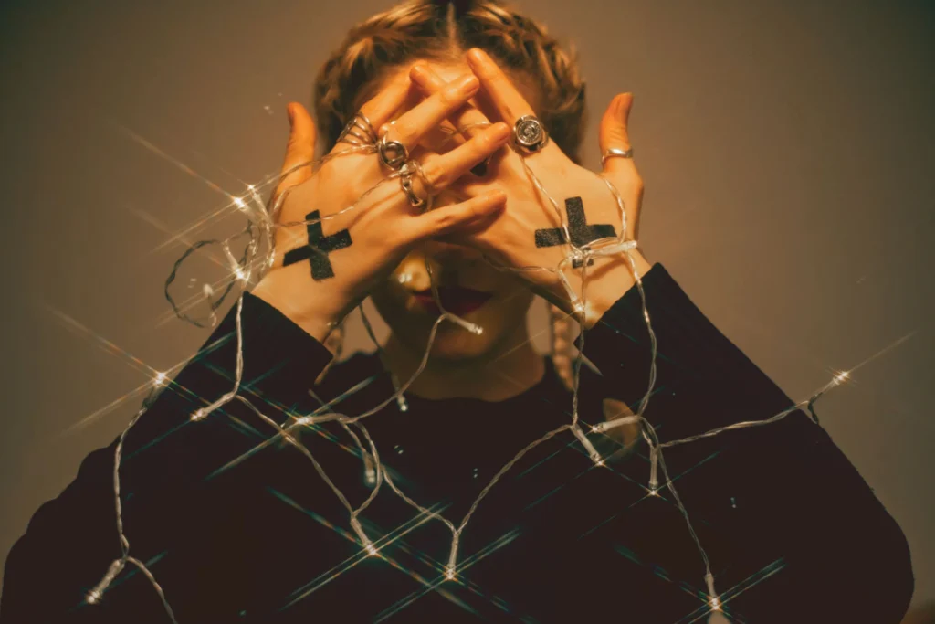 woman with crosses on hands covering her face