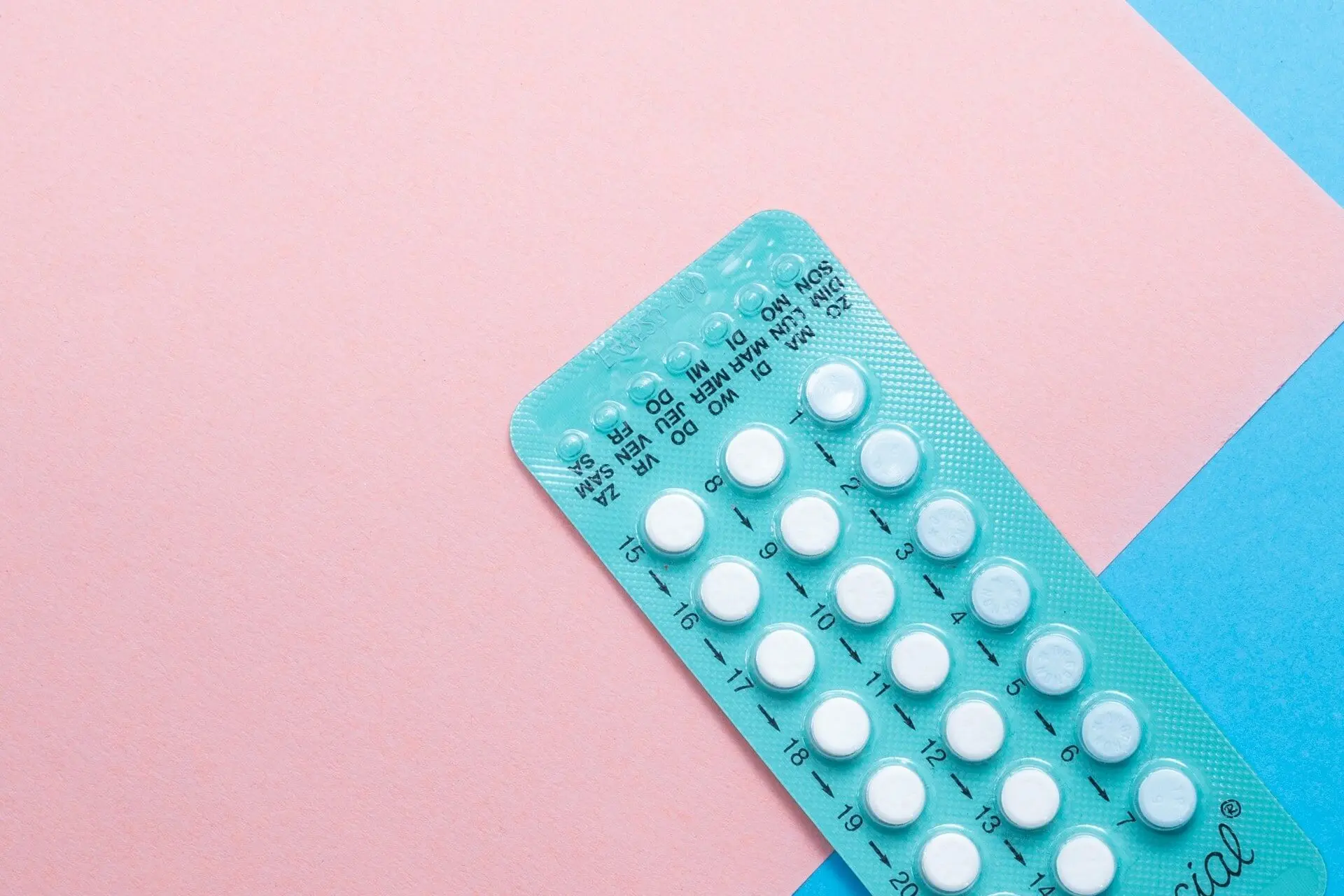 Blister pack with days of the week printed on it, set against a pink and blue background