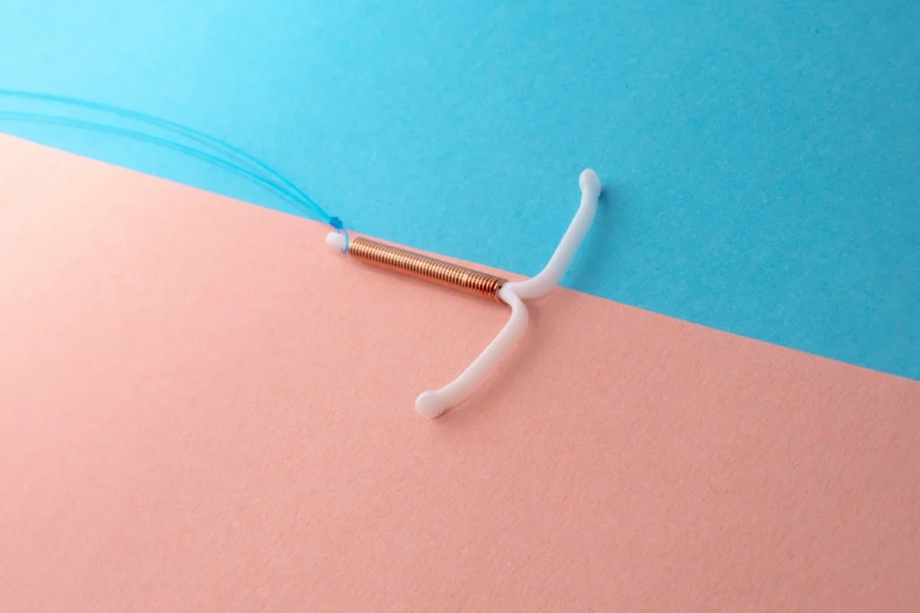 Copper IUD, a non-hormonal birth control device, on a pink and blue background