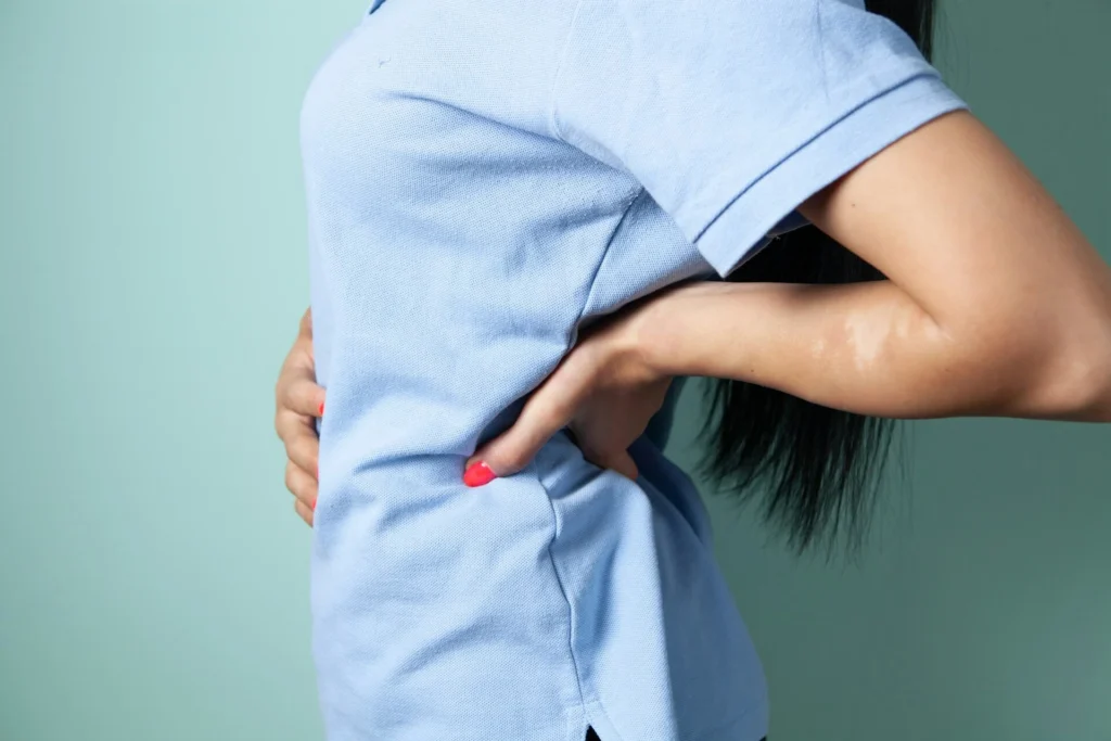 A woman holding her abdomen with muscle soreness, in need of heating pad pain relief