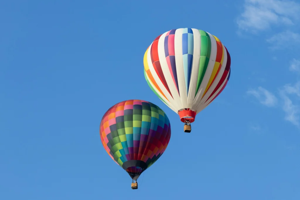 Two hot air balloons floating across the blue sky